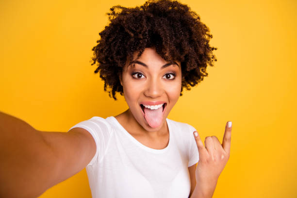 close up photo beautiful amazing she her dark skin lady arm hand rock fan concert metal music lover tongue out of mouth wear casual white t-shirt isolated yellow bright vibrant vivid background - video call imagens e fotografias de stock
