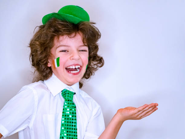 istock Saint Patrick celebrations over a light background. I am a smiling boy with a Irish flag on my cheek holding an imaginary subject in my hand. Copy space 1132936862