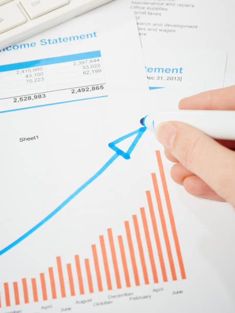 istock Female hand drawing rising arrow on positive-looking printed graph 1132939530