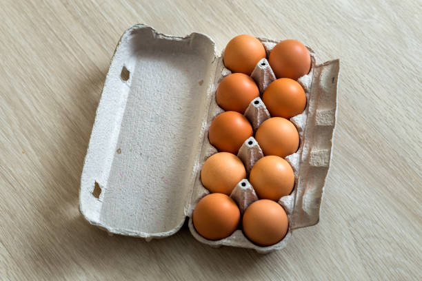 istock Hen eggs in open cardboard egg carton on kitchen table light copy space background. Healthy organic food and diet concept. 1132939645
