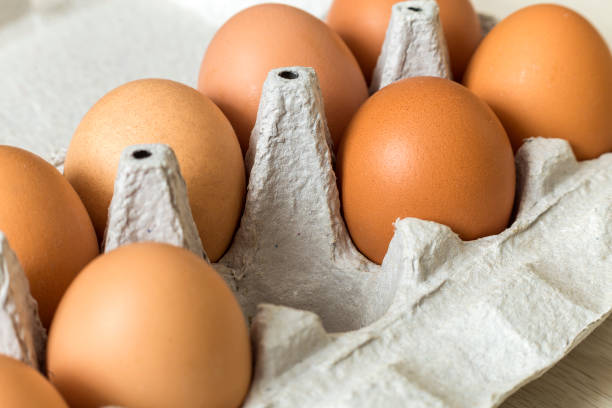 istock Hen eggs in open cardboard egg carton on kitchen table light copy space background. Healthy organic food and diet concept. 1132939724