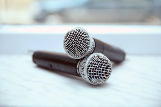 istock Two silver microphones isolated over white background . Two wireless microphones on the conference table. 1132940402