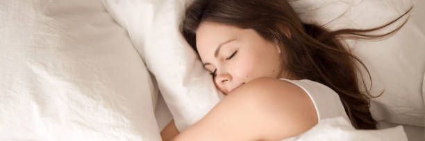 istock Above panoramic view young woman sleeping in bed hugging pillow 1132941028