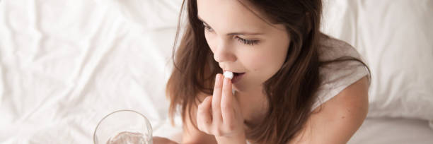 Closeup woman put pill in mouth holding glass with water Close up pale unhealthy woman put pill in mouth hold glass of water take painkiller relieve head ache pain healthcare concept horizontal photo banner for website header design with copy space for text abortion photos stock pictures, royalty-free photos & images