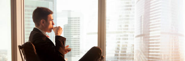 Horizontal photo businessman sitting on chair drink coffee look window at big city modern buildings rest after work. Vision motivation concept banner for website header design with copy space for text