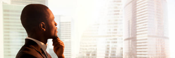 istock Close up side view black businessman standing near window thinking 1132941055