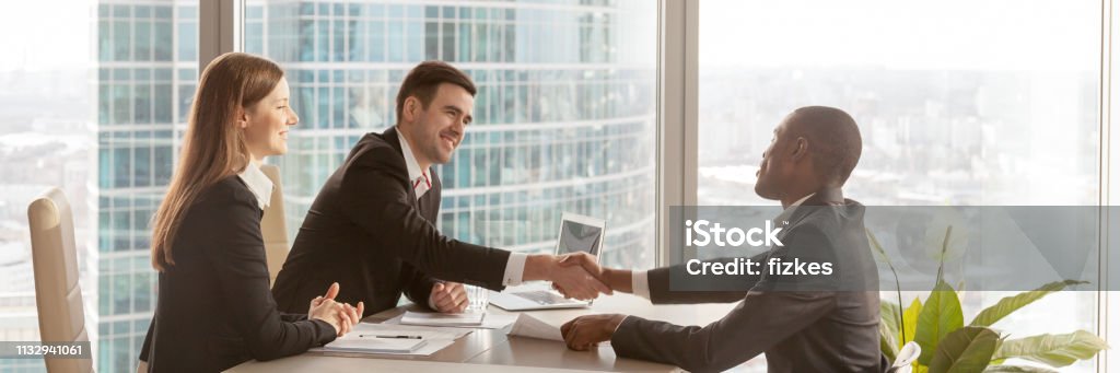 Horizontal image african boss congratulate business partner with successful negotiations Horizontal photo diverse businesspeople gather at modern office boardroom, black boss congratulate partner make deal effective negotiations signing agreement concept, banner for website header design Job Interview Stock Photo