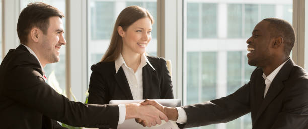 istock Horizontal image black and caucasian businesspeople greeting each other handshaking 1132941066