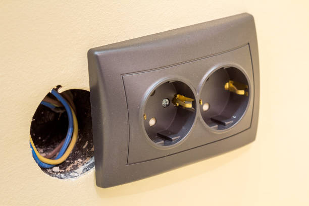 istock New gray power outlet socket with electric isolated colorful wires, plastic plug installation on light yellow plastered wall. Home interior, electricity supply concept. 1132943119