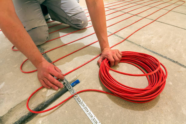 istock Electrician installing heating red electrical cable wire on cement floor in unfinished room. Renovation and construction, comfortable warm home concept. 1132943157