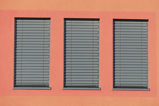 Windows with pulled down shutters Windows with dark shutters pulled down on a red house wall büro stock pictures, royalty-free photos & images