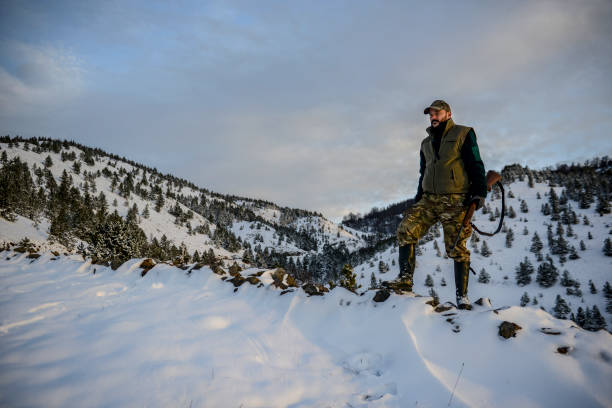istock Hunter standing on a snow-capped mountain top observing a serene view at dawn 1132949343