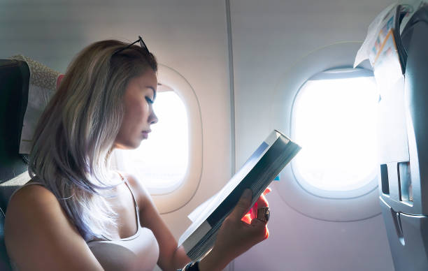 istock Woman reading magazine in airplane 1132950327