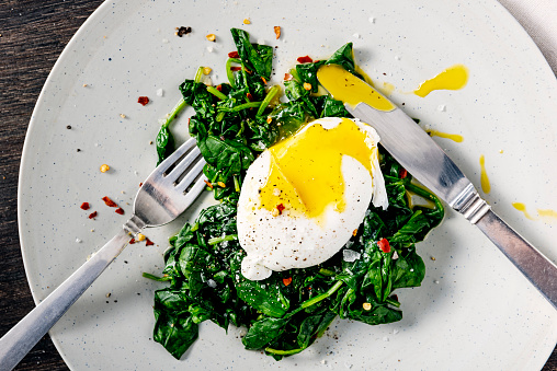 Overhead, close-up shot of a dish of eggs Benedict with wilted baby spinach leaves. Colour, horizontal with some copy space. Please see my others pictures in this series for more.