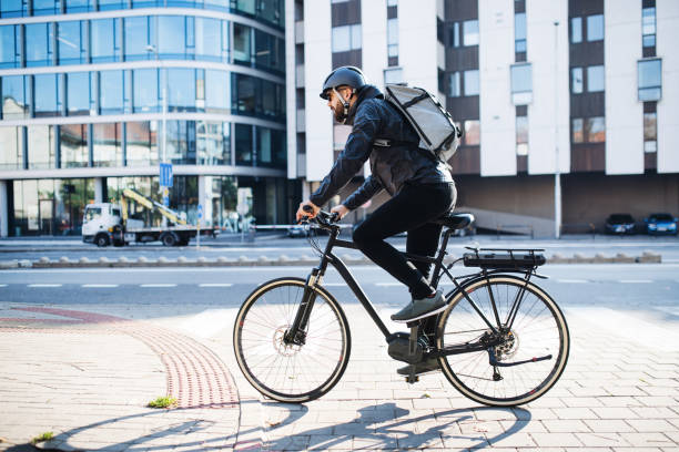 corriere maschile con pacchi di consegna biciclette in città. copiare lo spazio. - bicicletta elettrica foto e immagini stock