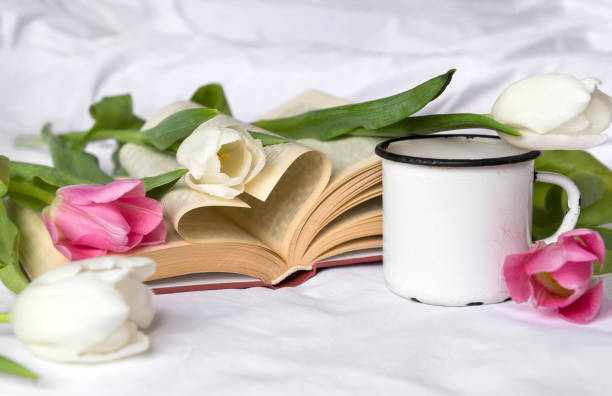 istock white,  pink tulips, white mug on white sheet, open book 1132953840