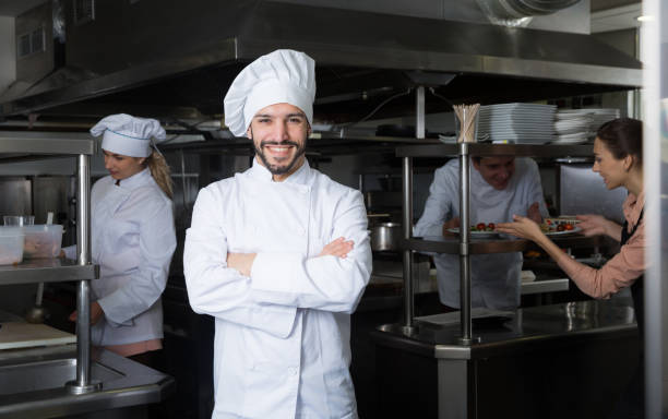 istock Chef in kitchen on background with employees 1132956456