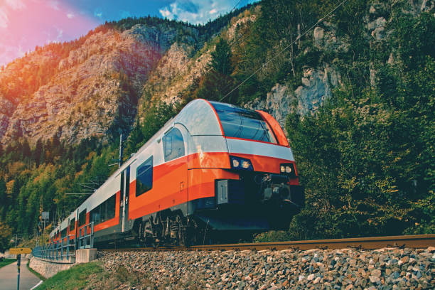 Red blue train in motion in Austrian alps mountains. High speed mountain train arrives at Hallstatt Obertraun train station in mountains. Location: resort village Hallstatt, Salzkammergut, Austria