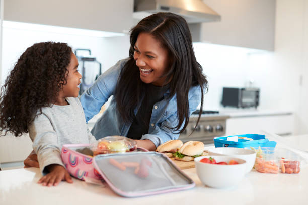 Daughter In Kitchen At Home Helping Mother To Make Healthy Packed Lunch Daughter In Kitchen At Home Helping Mother To Make Healthy Packed Lunch making a sandwich stock pictures, royalty-free photos & images