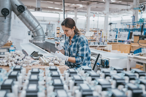 Mujer trabajadora industrial cables de soldadura de equipos de fabricación en una fábrica photo