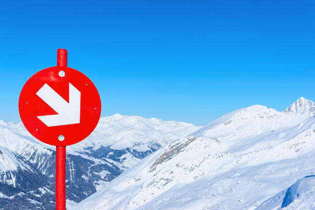 Red direction sign at Hintertux Glacier ski resort in Zillertal in Tyrol in Austria, winter in Alps. Alpine mountains with snow. Downhill fun. Family vacation. Blue sky and white slopes.