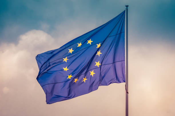 European Union flag flying the wind in sky, concept of unity between EU countries European Union flag waving in wind in colorful sky slightly cloudy. The official symbol of the EU. law european community european union flag global communications stock pictures, royalty-free photos & images