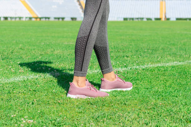 frau mit rosa turnschuhen steht auf fußballplatz mit der weißen linie laufbereit auf dem stadion - soccer field grass single line lawn stock-fotos und bilder