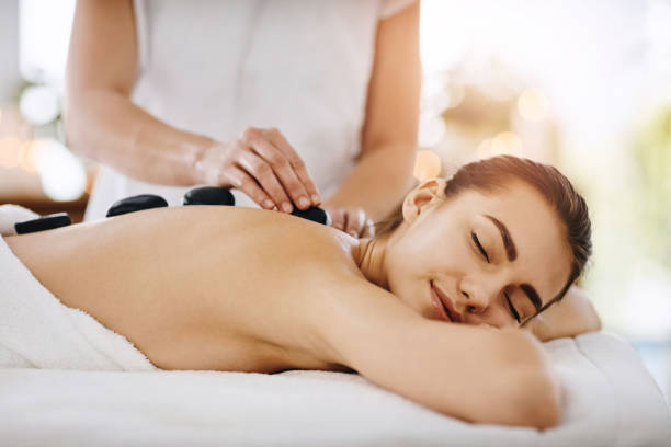 Feeling relaxed as the heat hits my body Shot of a young woman getting hot stone therapy at a spa massaging stock pictures, royalty-free photos & images