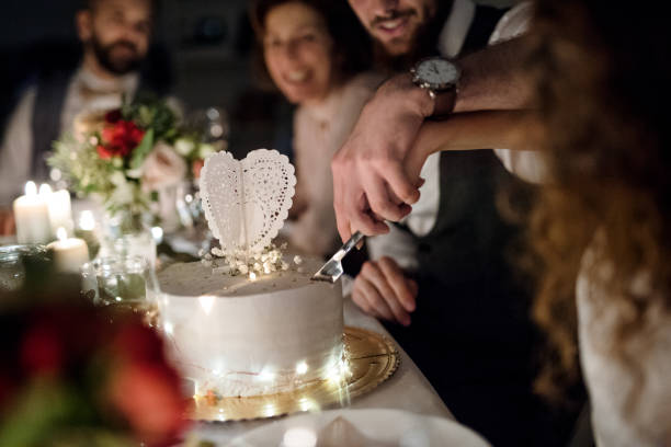 istock A midsection of young couple sitting at a table on a wedding, cutting a cake. 1132964007