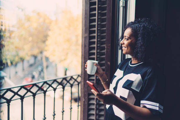 istock Cheerful woman texting at the balcony 1132964035