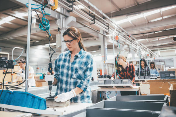 les jeunes employés de l'industrie travaillent sur la ligne de production à l'usine - ouvrier à la chaîne photos et images de collection