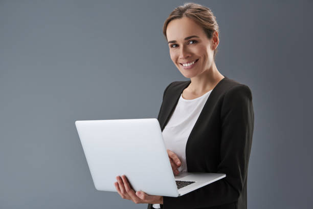 istock Charming lady looking at camera and holding laptop in hands 1132966113