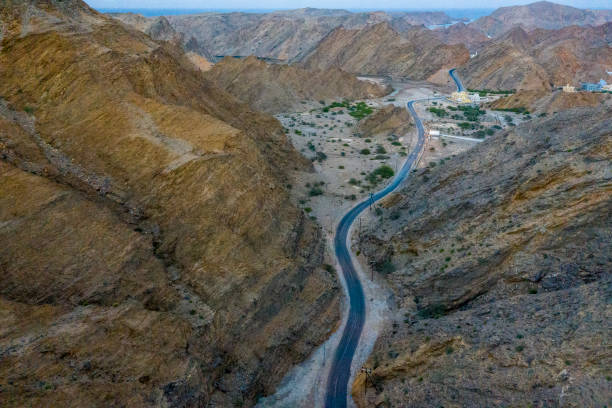 Long winding road cutting narrowly through the hillside Winding road going through a narrow cliff side and into the hills. Oman stock pictures, royalty-free photos & images