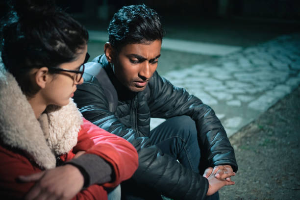 Serious discusses between young woman and man. Asian, Indian unhappy young man and woman discusses something serious together and they sit in park at night. south asia stock pictures, royalty-free photos & images