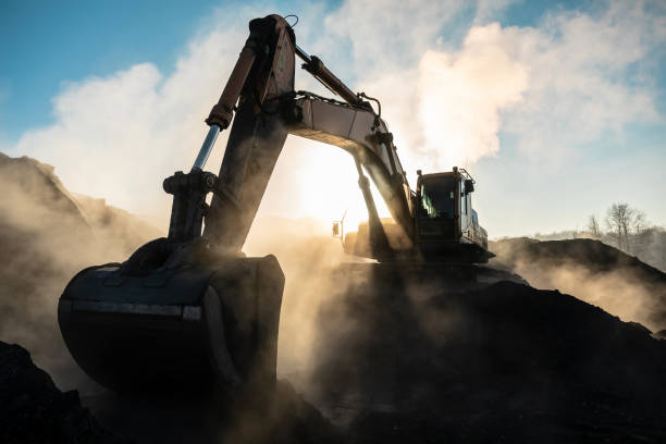 grande escavatore giallo nella miniera di carbone, carica la razza, con il sole splendente e il bel cielo blu sullo sfondo. macchine minerarie per l'estrazione di camion. tecnica nella miniera di carbone - macchinario edile foto e immagini stock