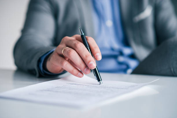 istock Business executive's hand holding pen over the contract, document on the white table, close-up. 1132973739