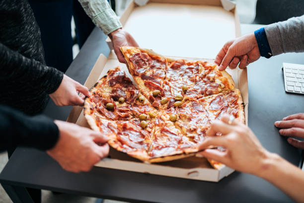 istock Close-up image of businesspeople sharing pizza. 1132973786
