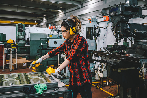Portrait of hard working female industry technical worker or engineer woman confident serious face turner standing works on automatic universal cnc vertical milling drill machine for production of metal structures in an industrial manufacturing factory company. XXXL