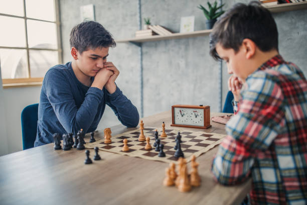 Two smart boys playing chess in school of chess Two young boys, playing chess in school of chess. chess photos stock pictures, royalty-free photos & images