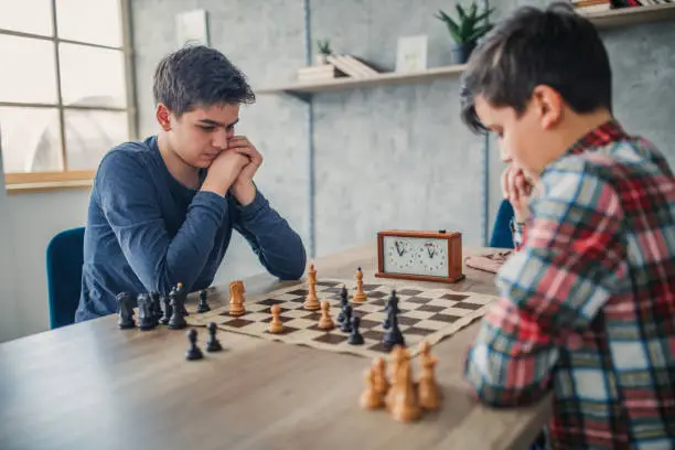 Two young boys, playing chess in school of chess.