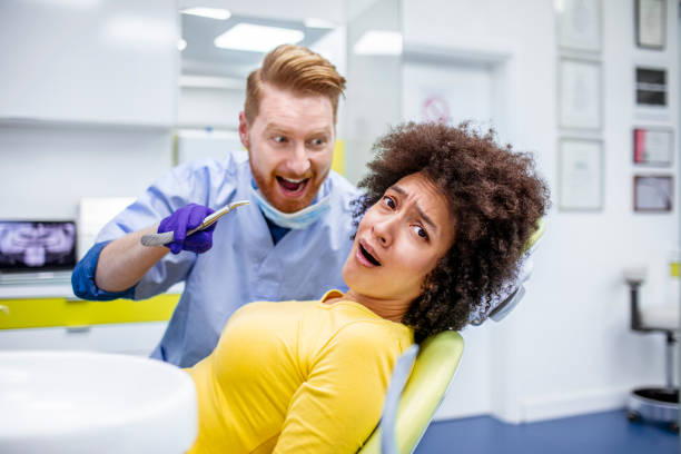 치아를 제거 하는 동안 공포 여자. 그녀의 닥터는 치과 니 퍼를 들고 있습니다. - dental equipment dental drill dentist surgical mask 뉴스 사진 이미지