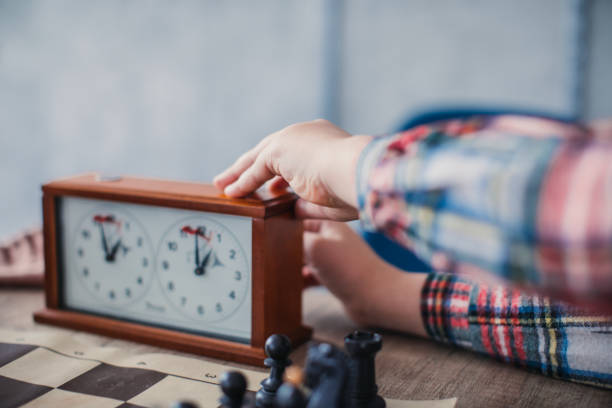 Time to make a move in game of chess One young boy, playing chess in school of chess alone, making a move. chess timer stock pictures, royalty-free photos & images