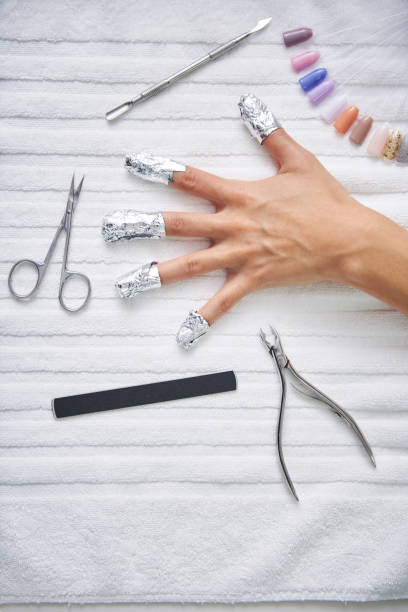 istock Female hand with strips of foil on fingers lying on table with manicure tools 1132978555
