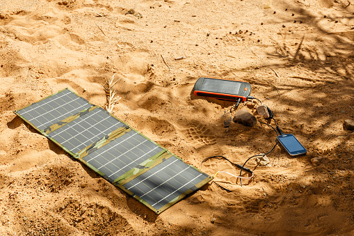 solar panel lying on the ground and charges the smart phone, the Sahara desert. Charge smart phone from the solar battery.