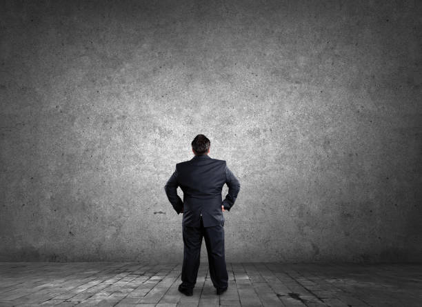 istock Businessman looking up at blank wall 1132980514