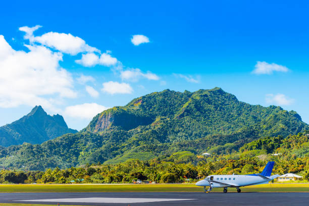 самолет в аэропорту на фоне горных пейзажей, остров айтутаки, острова кука. копирование пространства для текста - аитутаки фотографии стоковые фото и изображения