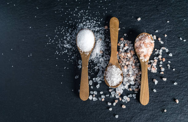 Different types of salt. Top view on three wooden spoons Different types of salt. Sea, Himalayan and kitchen salt. Top view on three wooden spoons on black background salt mineral photos stock pictures, royalty-free photos & images