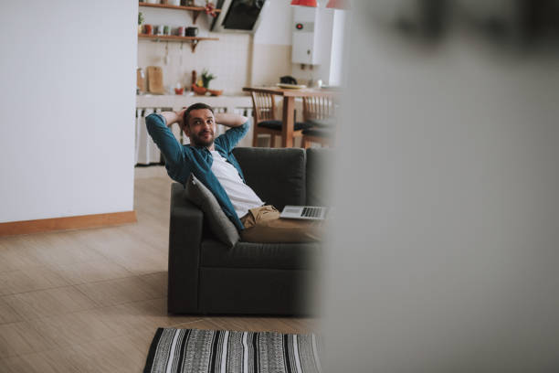 istock Handsome young man with arms behind his head resting at home 1132987180