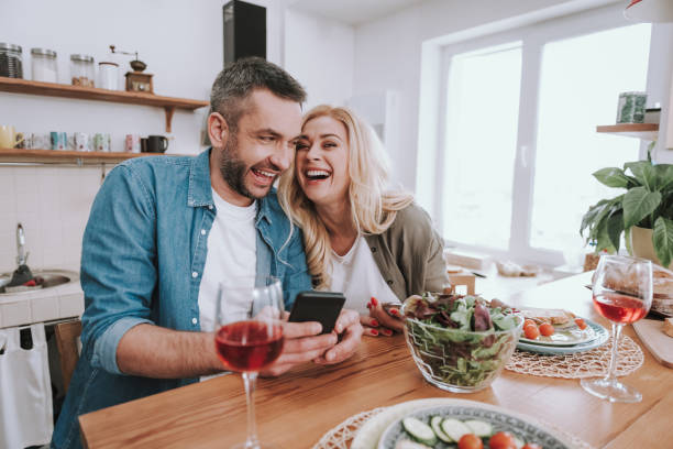 istock Cheerful couple using cellphones and having dinner at home 1132987255