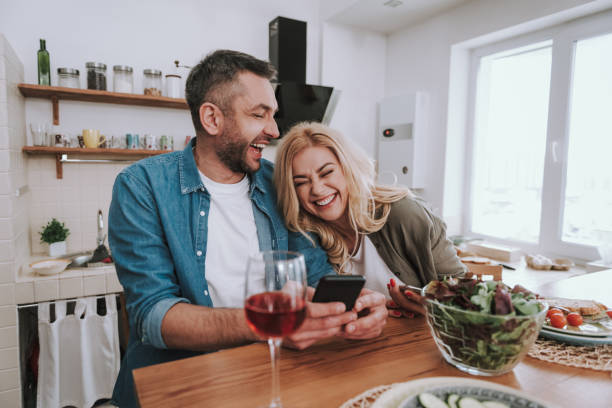 istock Cheerful happy couple using smartphones and having dinner at home 1132987267